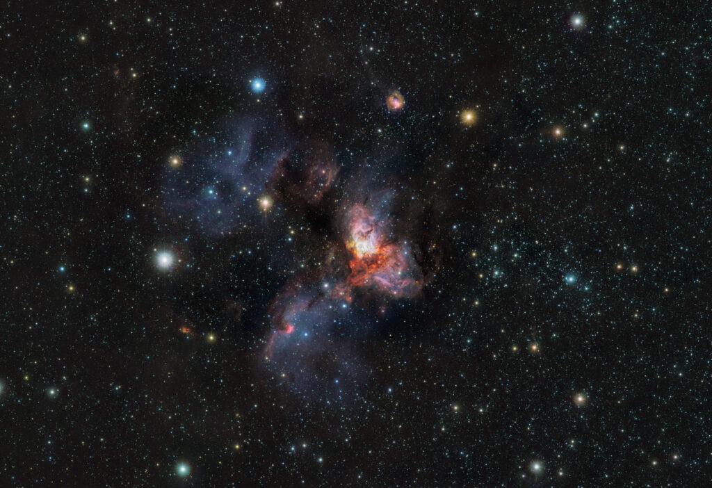 Le jeune amas RCW 38 observé en infrarouge par VISTA : un champ d’étoiles entourant des nuages de gaz lumineux et des zones sombres de poussières.